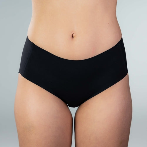 Close-up front view of model wearing Gudia black seamless hipster with V-shaped waistband and organic cotton crotch