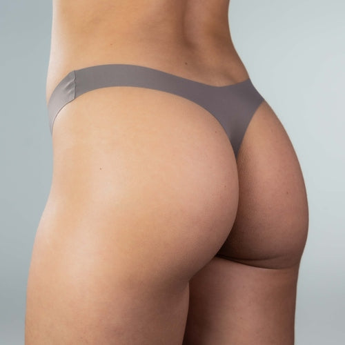 Close-up side-back view of model wearing Gudia grey organic cotton crotch seamless thong, peach-hip shaping and seamless edge for invisible wear and natural contour