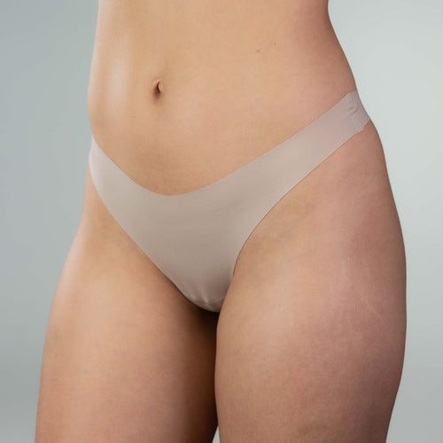 Side-front close-up of model wearing Gudia sand seamless thong, V-shaped waistband and soft fabric for a smooth, everyday fit
