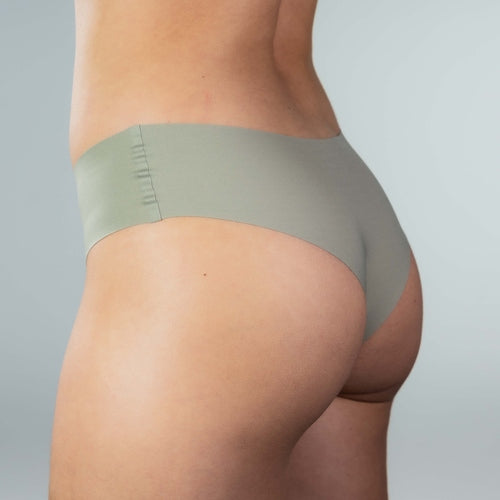 Side view of model wearing Gudia green seamless Brazilian underwear with mid-rise fit, soft waistband, and organic cotton crotch
