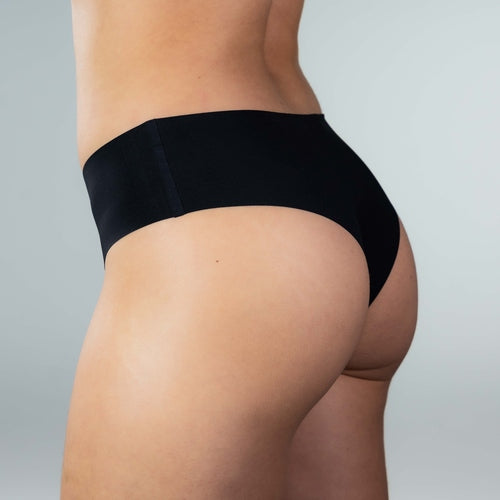 Side view of model wearing Gudia black seamless Brazilian underwear with soft waistband, mid-rise fit, and organic cotton crotch