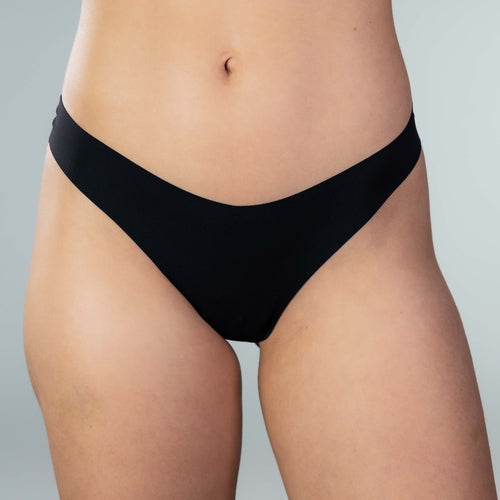 Front close-up of model wearing Gudia black seamless thong, V-shaped waistband, seamless front, and organic cotton crotch for breathable, irritation-free wear