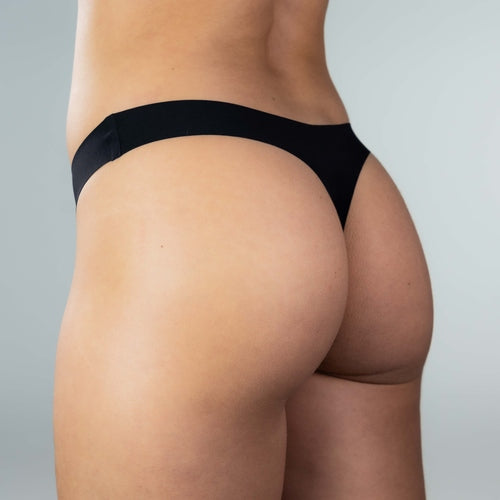 Side-back close-up of model wearing Gudia black seamless thong, seamless peach-hip fit with soft stretch fabric and organic cotton crotch for breathable comfort