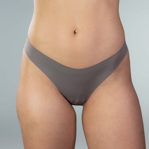 Close-up front view of model wearing Gudia grey seamless thong ,organic cotton crotch ,V-shaped waistband and seamless front for soft, irritation-free comfort