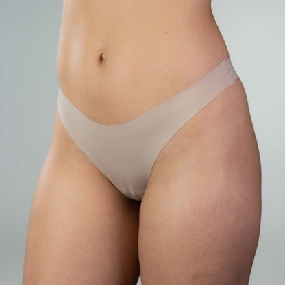 Side-front close-up of model wearing Gudia sand seamless thong, V-shaped waistband and soft fabric for a smooth, everyday fit
