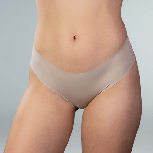 Front close-up view of model wearing Gudia sand seamless Brazilian underwear with mid-rise fit, soft waistband and organic cotton crotch designed for everyday freshness and breathability